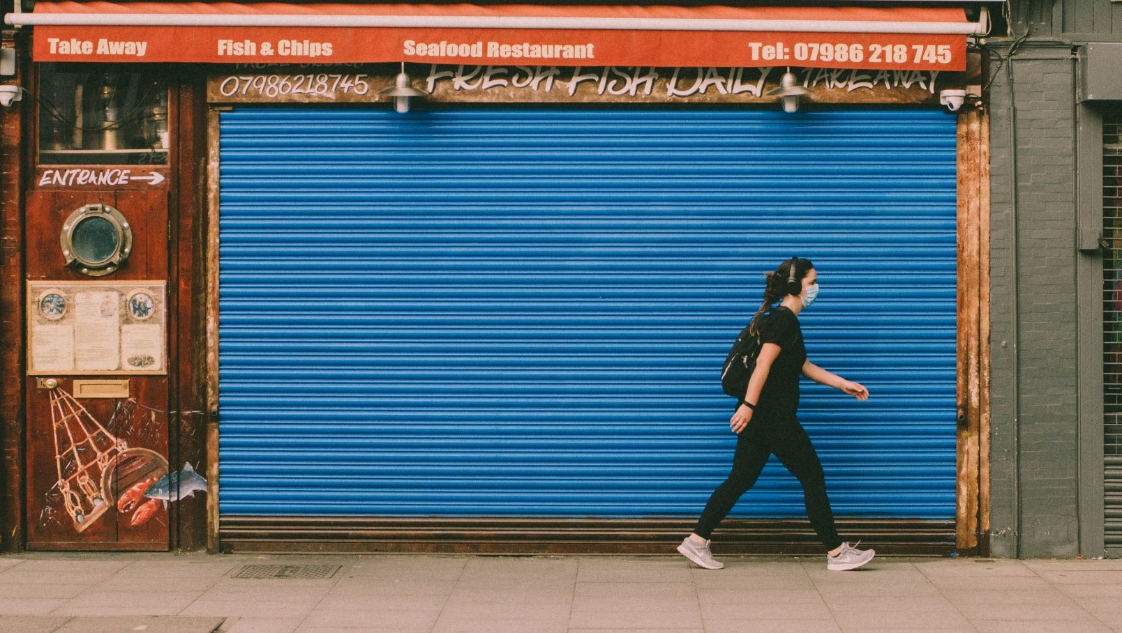 Woman walking in front of restaurant on street